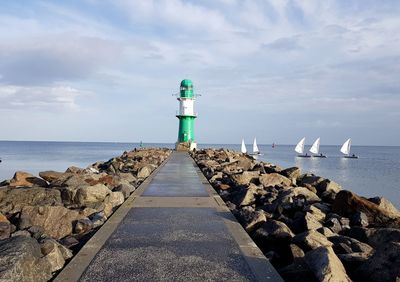 Lighthouse by sea against sky