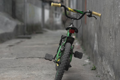 Close-up of bicycle on footpath against wall