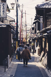 Rear view of people walking on street amidst buildings