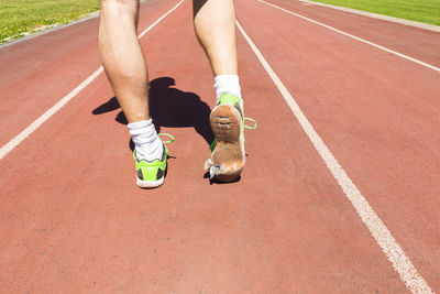 Low section of athlete running with torn shoes on track