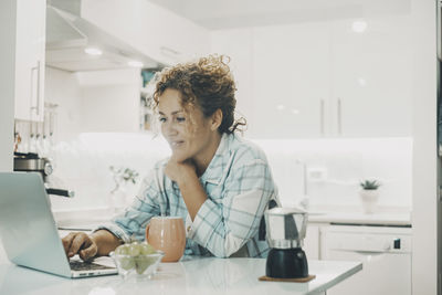 Side view of young woman using digital tablet at home