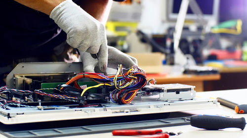 Midsection of man repairing computer equipment on table