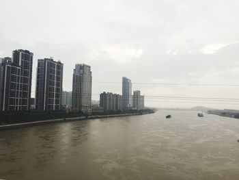 Sea by buildings against sky in city