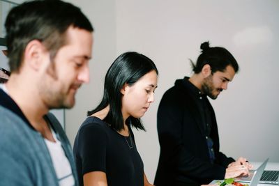 Three people at stand-up desk in office