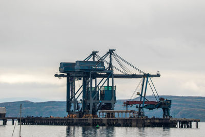 Cranes at pier against sky