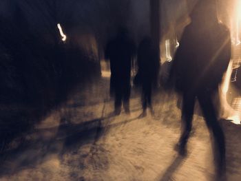 Silhouette people walking on illuminated road at night