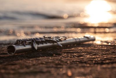 Close-up of water on table at beach against sky during sunset