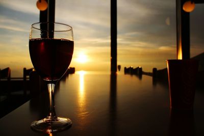 Close-up of wine on table against sky at sunset