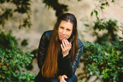 Young woman standing against plants