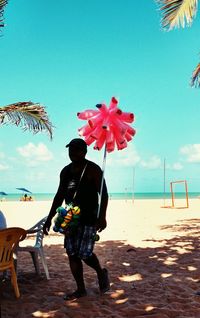 Man selling toys at beach against sky