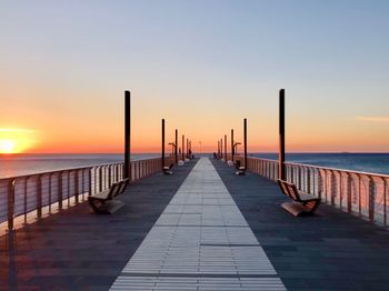 Pier over sea against sky during sunset