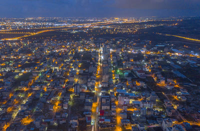 High angle view of illuminated city by sea against sky