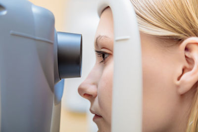 A young girl at the reception at the ophthalmologist checks her eyesight on a special apparatus. 