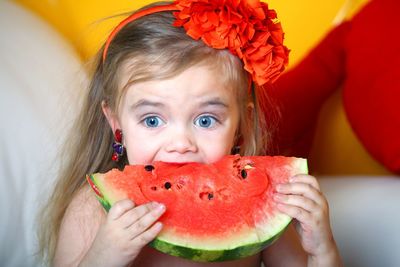 A 3 year old girl eats a watermelon.