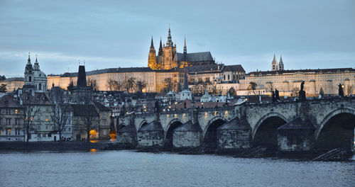 Arch bridge over river against buildings in city