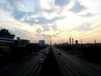 Cars on street in city against sky during sunset