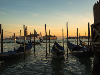 Boats moored in sea at sunset