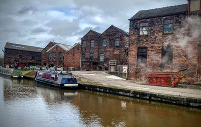 Buildings by canal against sky in city