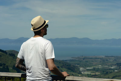 Rear view of man looking at mountains against sky