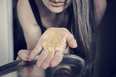 Midsection of woman showing gold glitters while holding plate