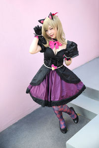 Full length of young woman standing by wall indoors