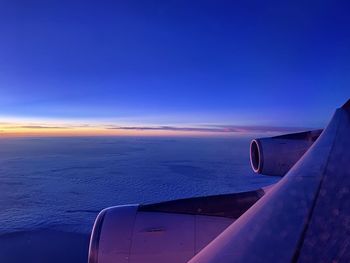 Cropped image of airplane wing against sky during sunset