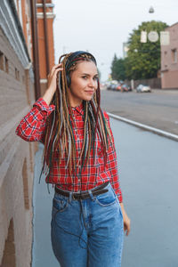 Beautiful young woman listening music while walking on footpath in city