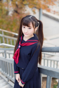 Portrait of young woman standing by railing