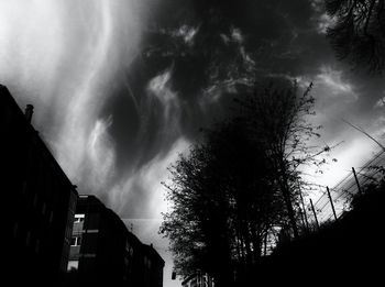 Low angle view of silhouette trees and buildings against sky