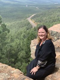 Portrait of smiling woman sitting on rock