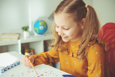 Cute girl painting while sitting at home
