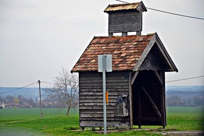 Wooden cabin on field against clear sky