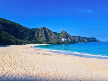 Scenic view of beach against clear blue sky