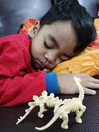 Cute boy sleeping by toys on sofa at home