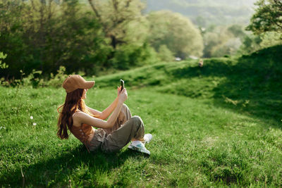 Side view of woman sitting on grassy field