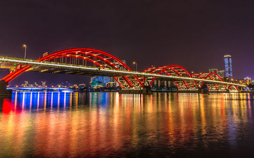 Illuminated bridge over river at night