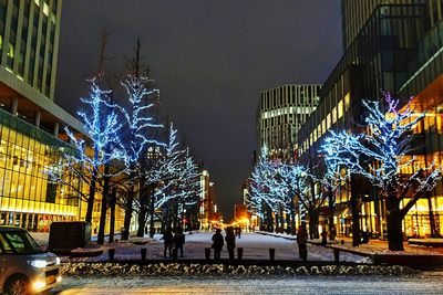 Illuminated street amidst buildings in city at night