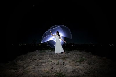 Full length of man standing against illuminated lights at night