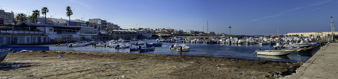 Boats moored at harbor against clear sky