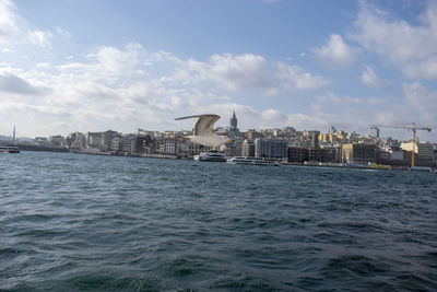 Sea and buildings in city against sky