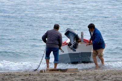 Rear view of men standing at beach