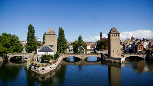 Bridge over river by buildings against clear sky