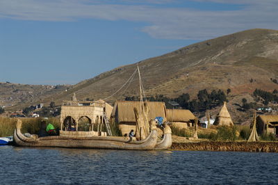 Boats in lake by buildings against sky