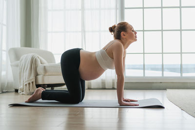 Full length of woman exercising on floor at home