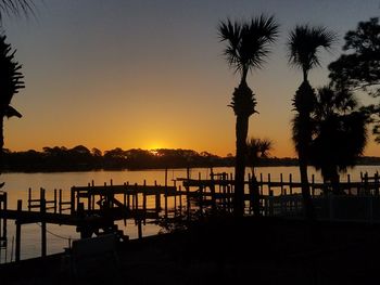 Silhouette trees by lake against sky during sunset