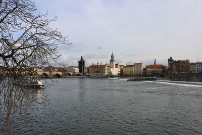 Buildings at waterfront against cloudy sky