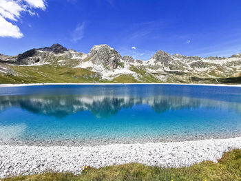 Scenic view of lake by mountains against blue sky