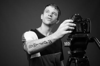 Portrait of man photographing against black background