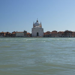 View of buildings by mosque against clear sky