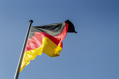Low angle view of german flag against clear blue sky